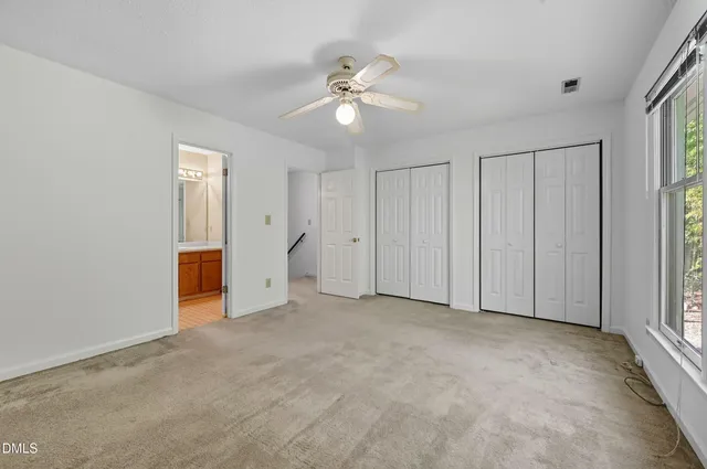 an empty room with windows and chandelier fan