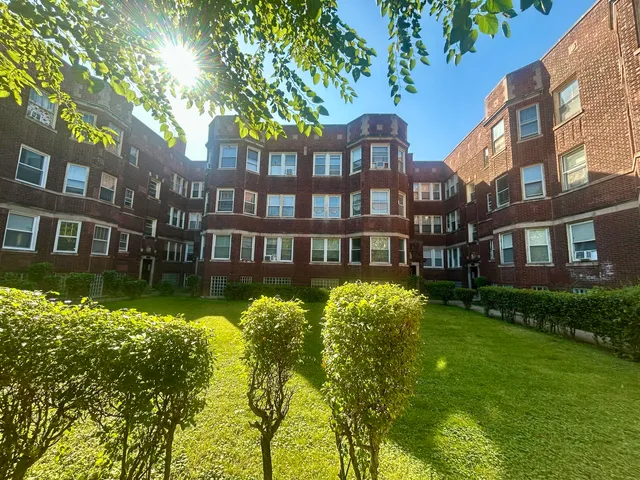 a front view of a residential apartment building with a yard and swimming pool