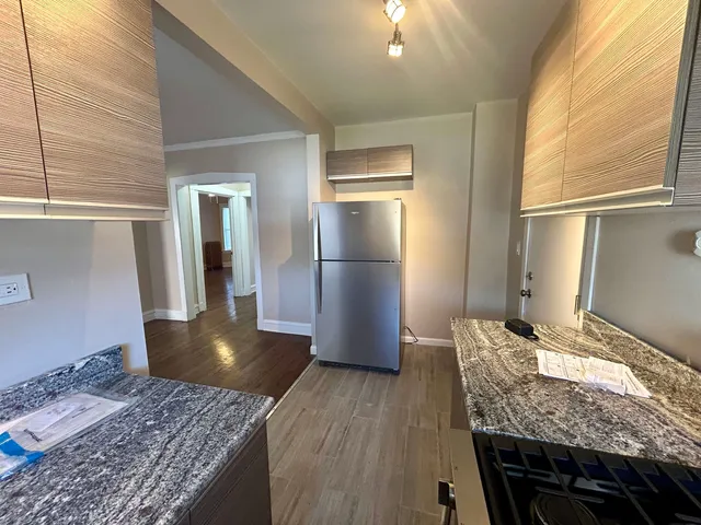 a kitchen with stainless steel appliances granite countertop wooden cabinets and wooden floor
