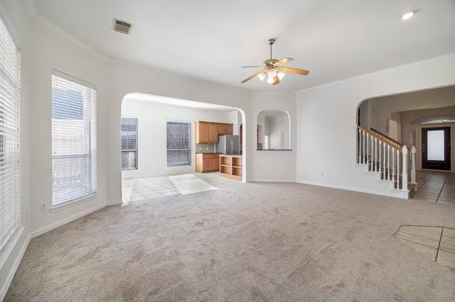 an empty room with chandelier fan and windows