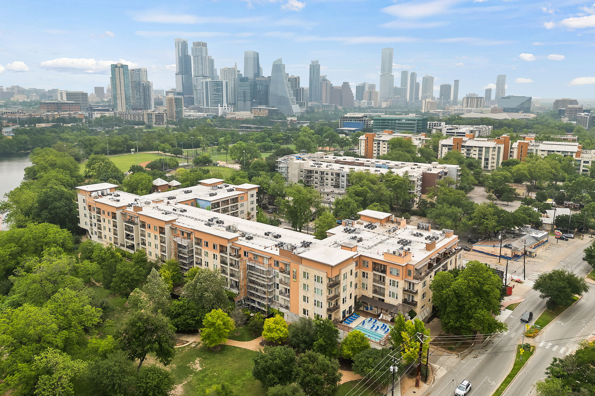 1900 Barton Springs Road, Unit 5015 Austin, TX 78704 - Photo 1 of 1 Multi-story building featuring balconies, a swimming pool, and surrounding green spaces