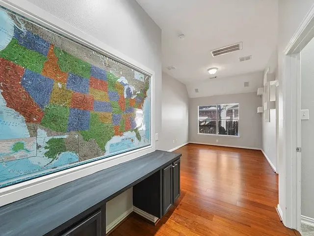 a view of an empty room with chandelier fan and wooden floor