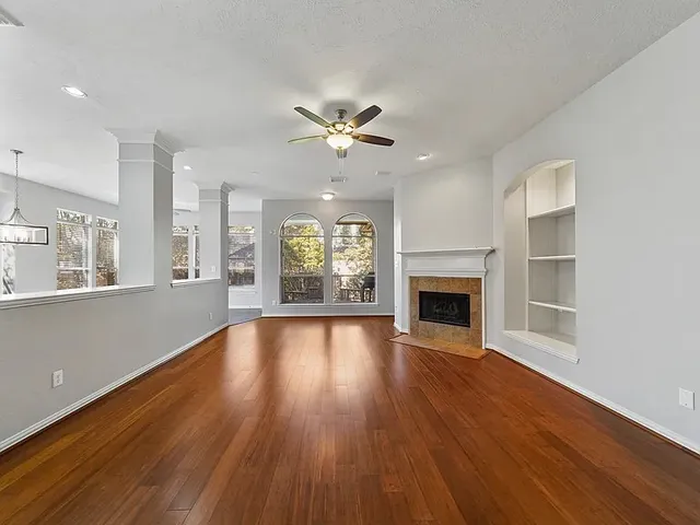 an empty room with fireplace wooden floor and windows