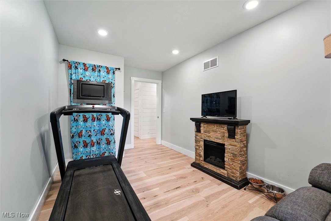 3576 Plymouth Ridge Road Kingsville, OH 44048 - Photo 28 of 43 Workout room featuring a fireplace, light wood-style flooring, and recessed lighting