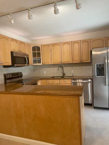 a kitchen with stainless steel appliances granite countertop a stove a sink and a refrigerator with wooden floor