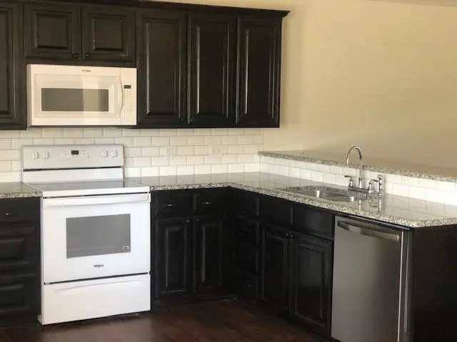 a kitchen with granite countertop a sink and a stove