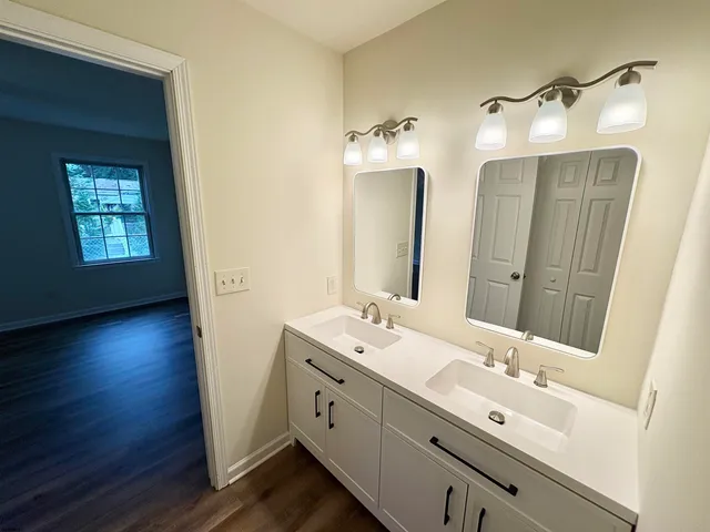 a bathroom with a double vanity sink and mirror with wooden floor