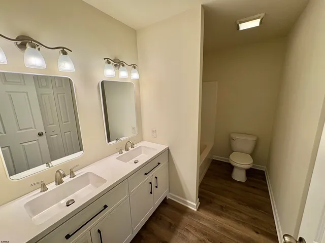 a bathroom with a double vanity sink toilet and mirror