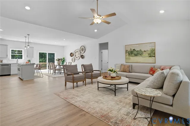 a view of an empty room with wooden floor and kitchen view