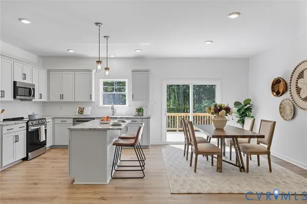 a open kitchen with granite countertop a stove top oven a sink dishwasher a dining table and chairs with wooden floor