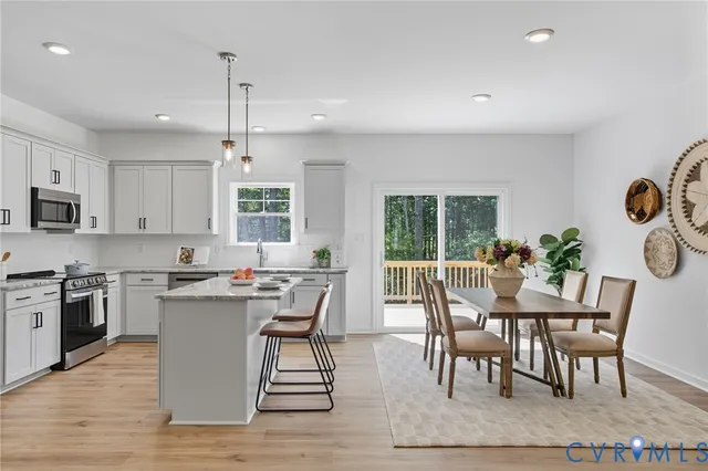 a open kitchen with granite countertop a stove top oven a sink dishwasher a dining table and chairs with wooden floor