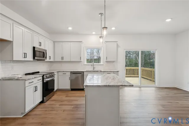 a view of a dining room and livingroom with furniture wooden floor a rug a fireplace