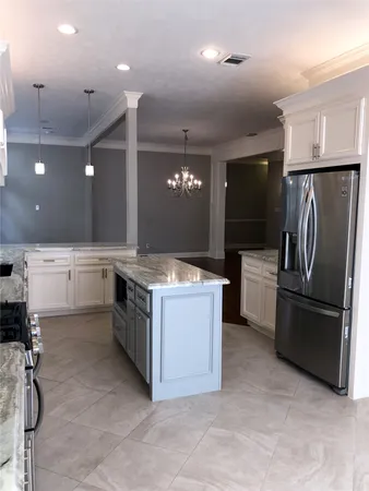 a large kitchen with stainless steel appliances kitchen island a large counter top a sink and a refrigerator