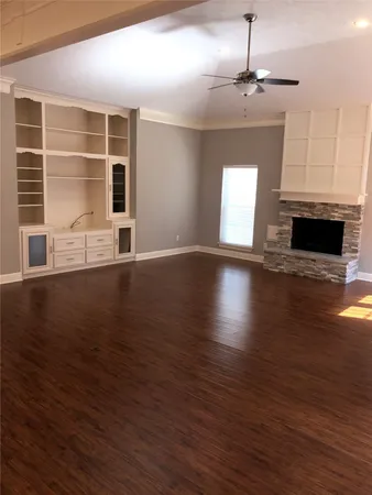 an empty room with wooden floor fireplace and windows