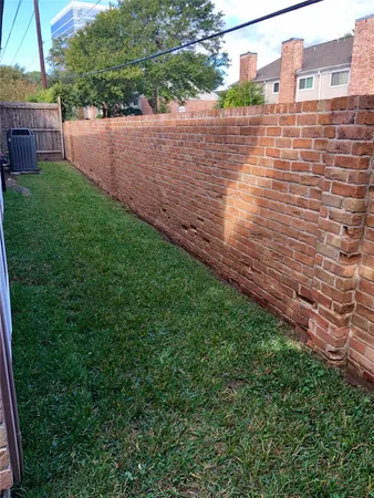 a view of a backyard with plants and brick wall