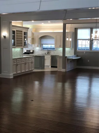 a view of a kitchen with kitchen island wooden floors and stainless steel appliances