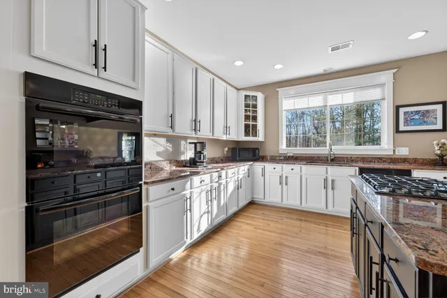 a kitchen with stainless steel appliances granite countertop sink stove top oven and cabinets