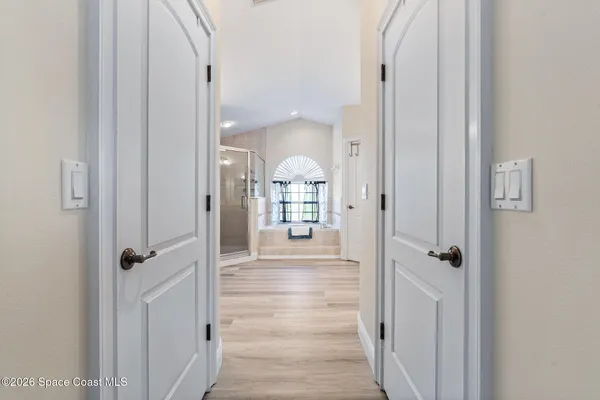 a view of a hallway with wooden floor windows and chandelier