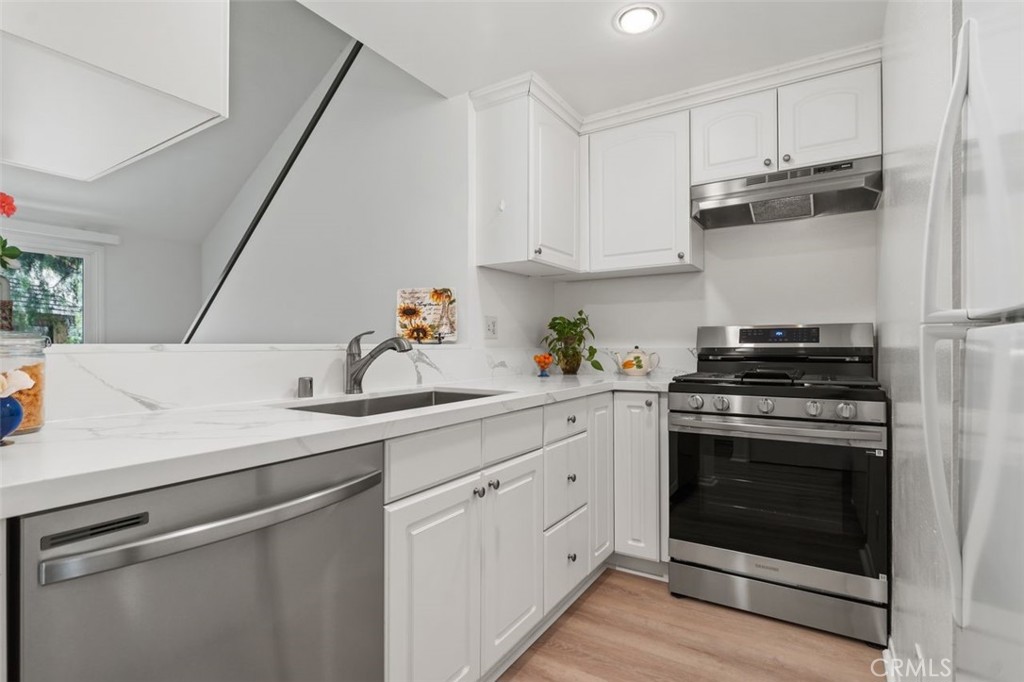 89 Lemon Grove Irvine, CA 92618 - Photo 10 of 34 a kitchen with cabinets stainless steel appliances and wooden floor