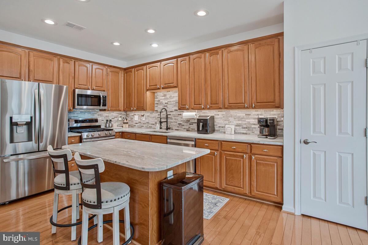3515 Cromarty Lane Edgewater, MD 21037 - Photo 9 of 53 a kitchen with granite countertop wooden cabinets a refrigerator a stove a sink with a dining table and chairs