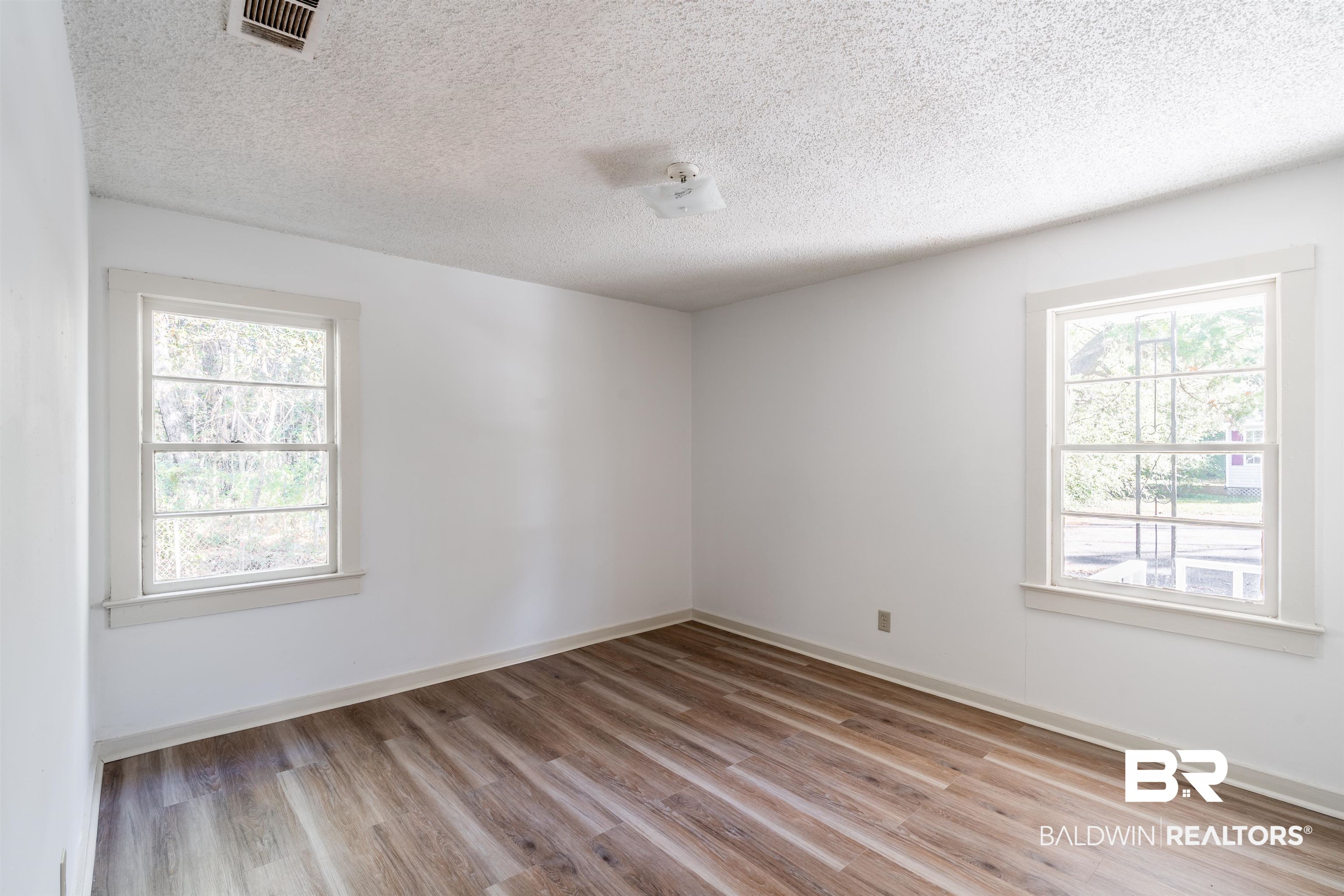 3900 Brookmont Drive Mobile, AL 36605 - Photo 12 of 19 Empty room featuring light hardwood / wood-style floors, a textured ceiling, and plenty of natural light