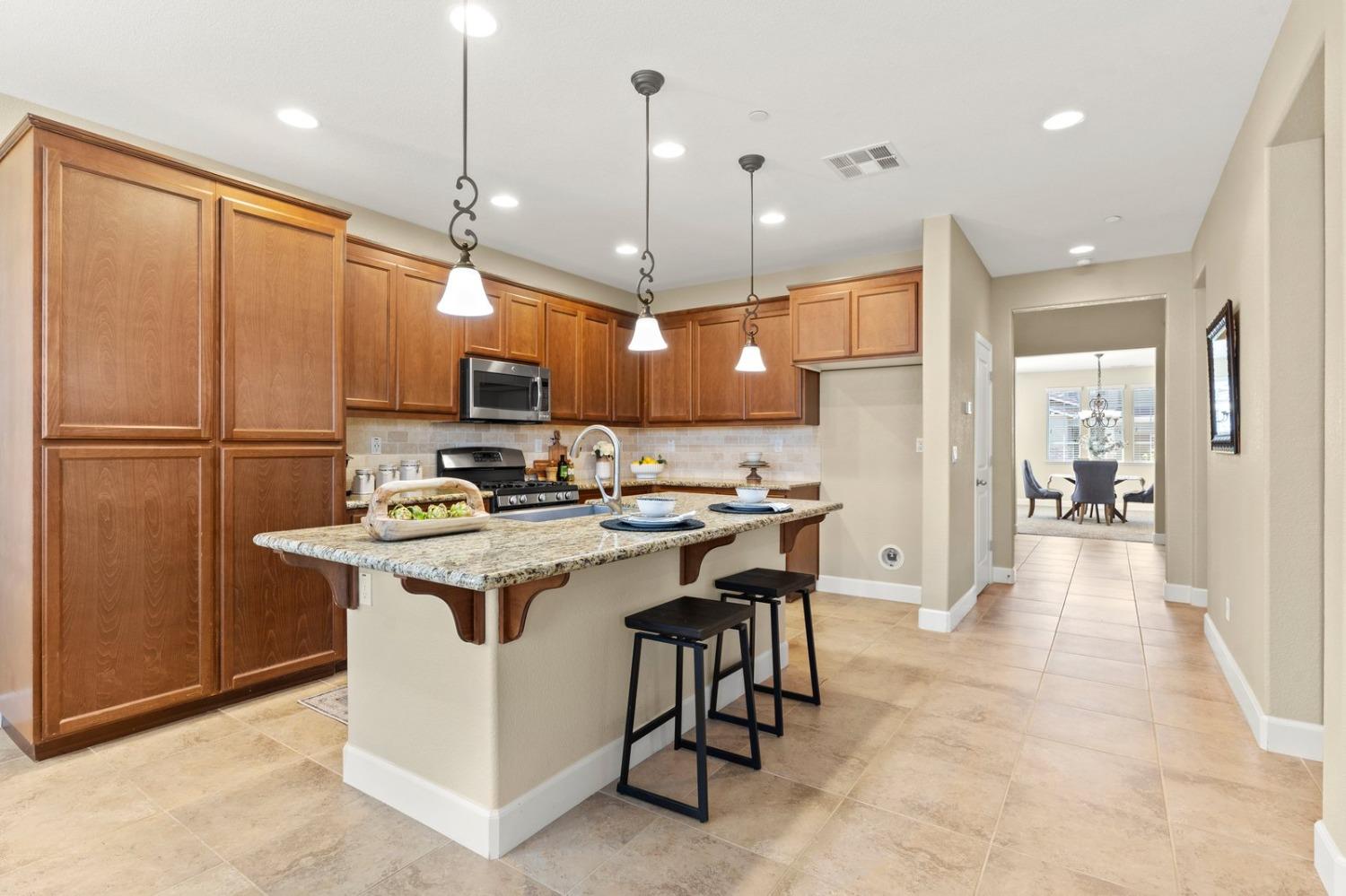 6307 Lookout Pass Way Rocklin, CA 95765 - Photo 24 of 72 a kitchen with stainless steel appliances granite countertop a refrigerator a sink dishwasher a oven and a dining table with wooden floor
