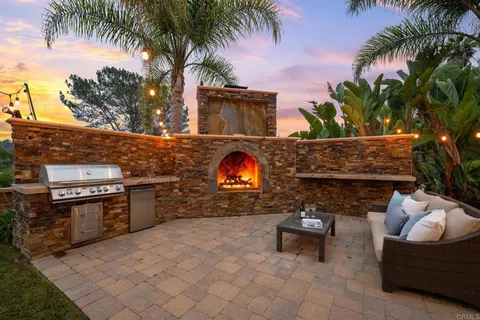 a view of a backyard with couches plants and large trees