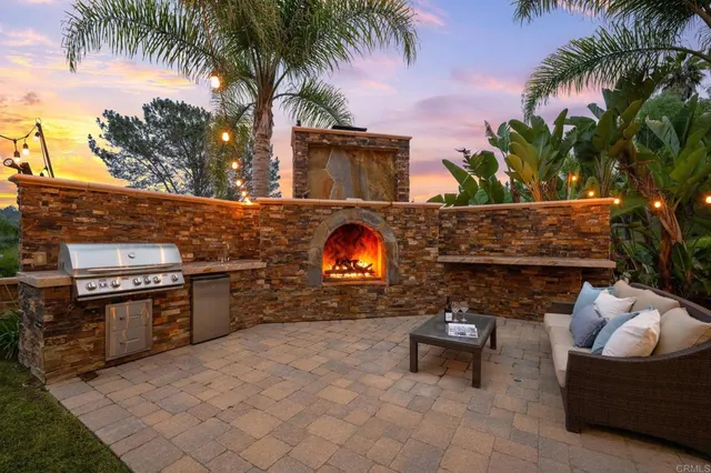 a view of a backyard with couches plants and large trees