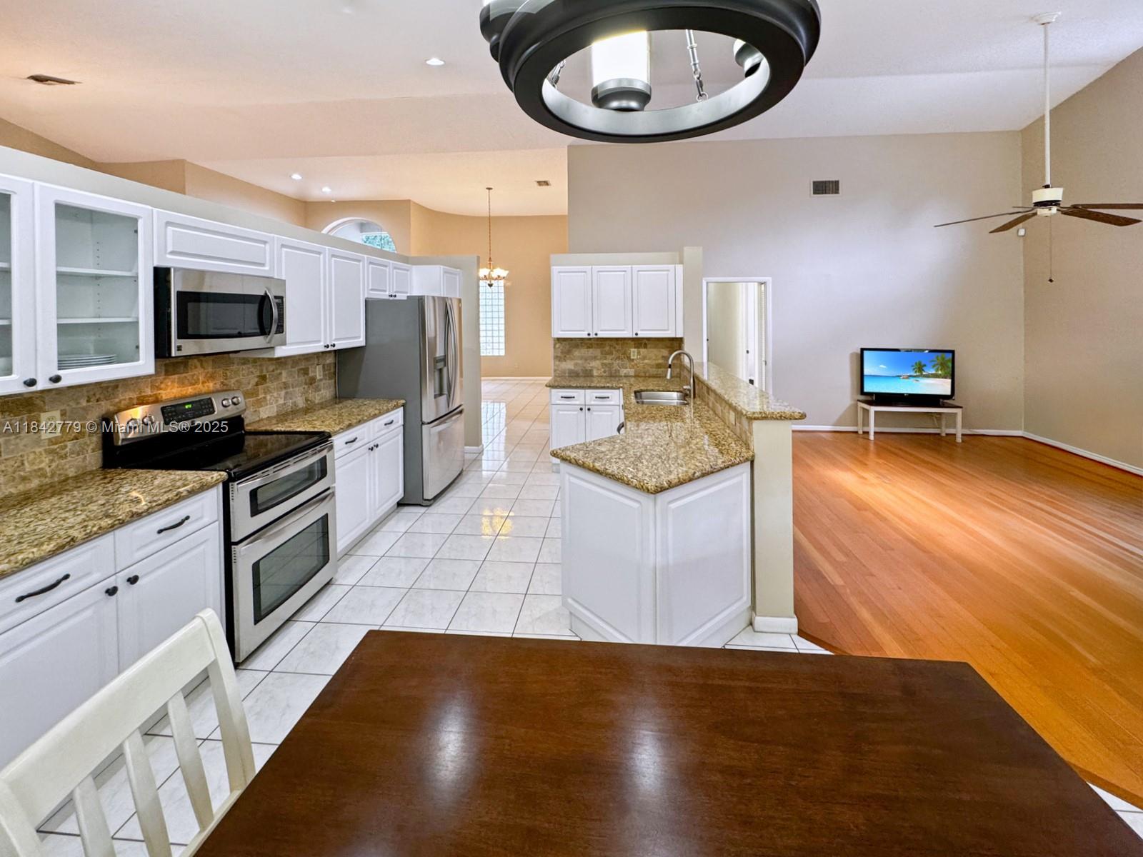 10621 Paris Street Cooper City, FL 33026 - Photo 18 of 58 a kitchen with a stove a sink and a refrigerator