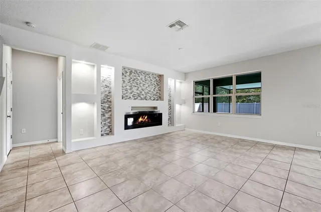 a view of an empty room with window and fire place