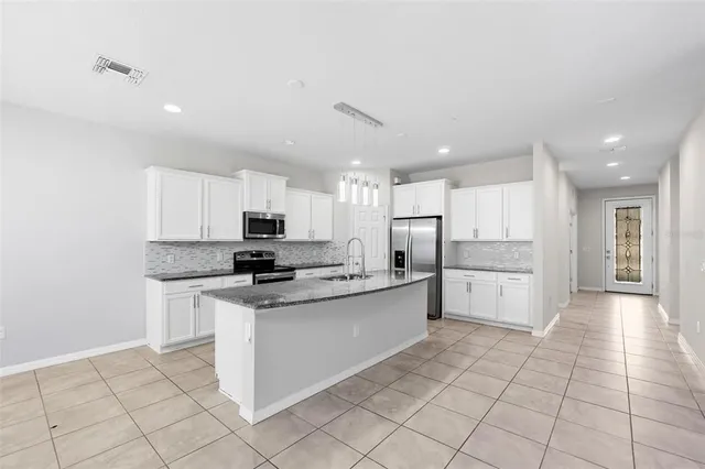 a kitchen with a sink a white cabinets and stainless steel appliances