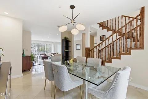 a dining room with wooden floor a chandelier a wooden table and chairs