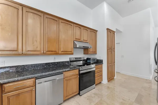 a kitchen with stainless steel appliances granite countertop a stove a sink and a refrigerator with cabinets