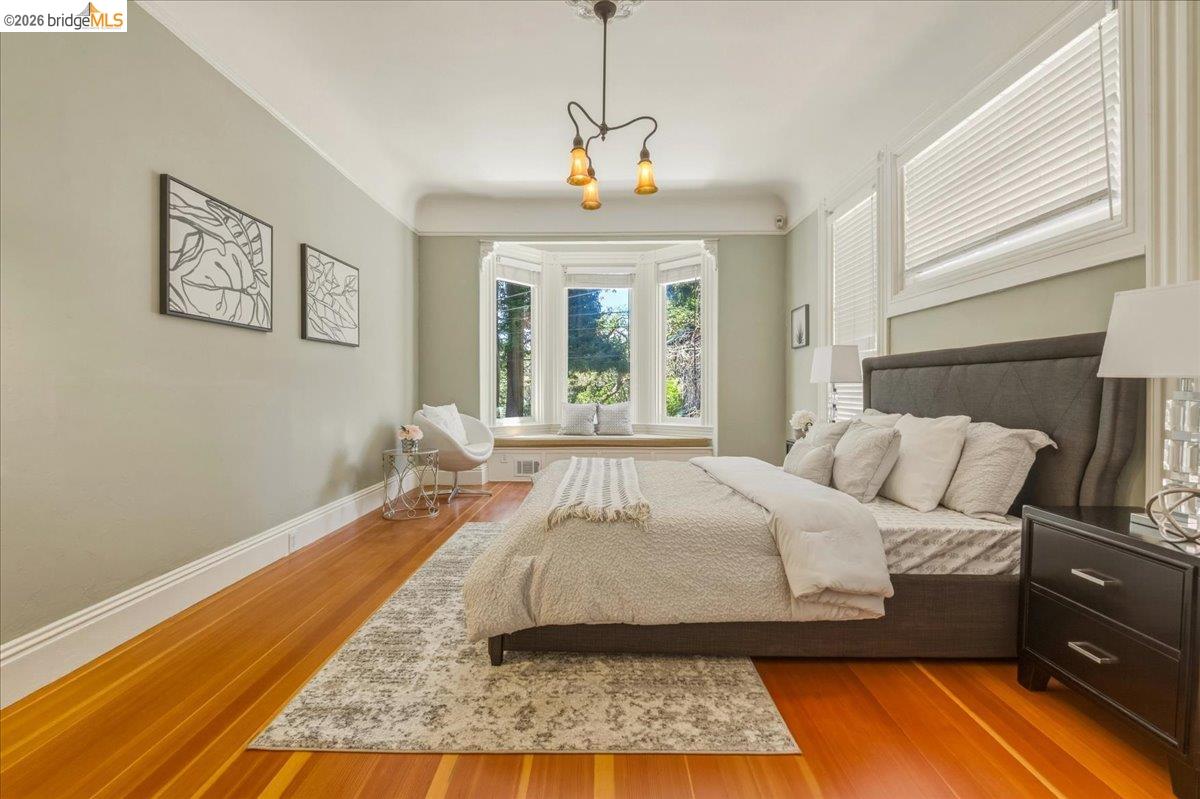 1631 La Vereda Road Berkeley, CA 94709 - Photo 20 of 42 Room featuring a prominent bay window with a built-in bench, wood-finish flooring, and a decorative ceiling light fixture