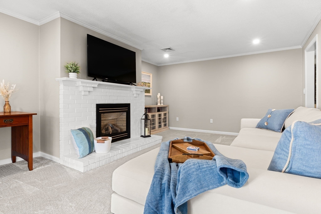 167 Village Post Road, Unit 167 Danvers, MA 01923 - Photo 11 of 42 a living room with furniture a fireplace and a flat screen tv