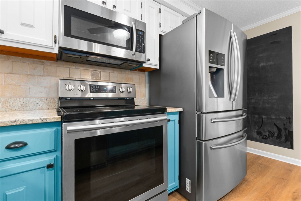 167 Village Post Road, Unit 167 Danvers, MA 01923 - Photo 8 of 42 a kitchen with stainless steel appliances wooden cabinets and a stove top oven