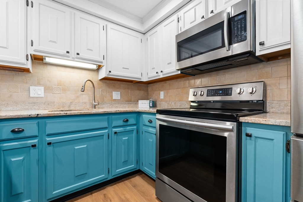167 Village Post Road, Unit 167 Danvers, MA 01923 - Photo 9 of 42 a kitchen with stainless steel appliances granite countertop white cabinets and a stove top oven