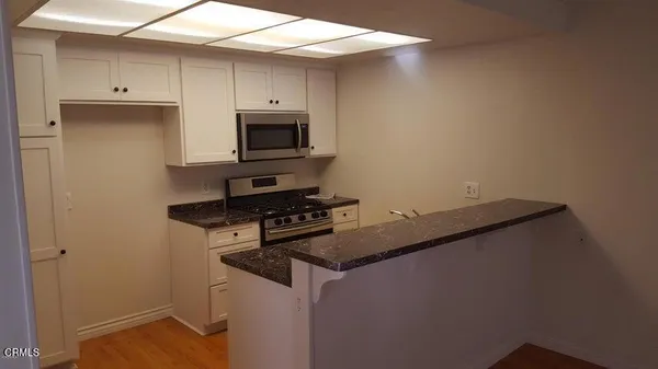 a kitchen with granite countertop cabinets stainless steel appliances and a counter space