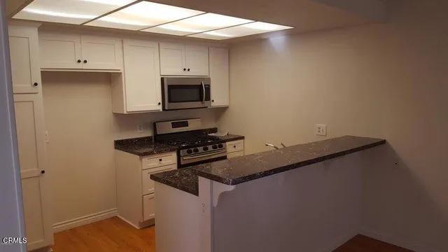 a kitchen with granite countertop cabinets stainless steel appliances and a counter space