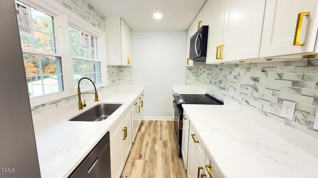 a kitchen with a sink and a stove with wooden floor