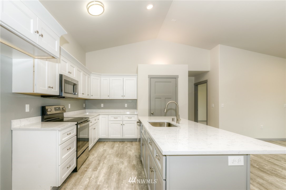 18430 Guava Street Southwest Rochester, WA 98579 - Photo 4 of 36 a kitchen with a sink a stove top oven and white kitchen