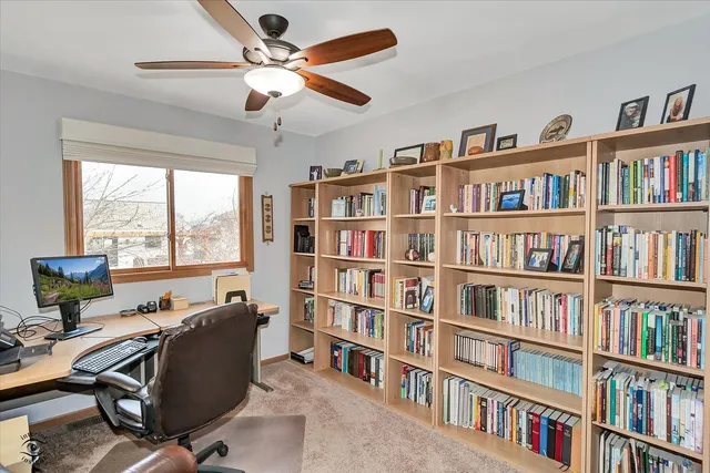 a view of a workspace with bookshelf and a window