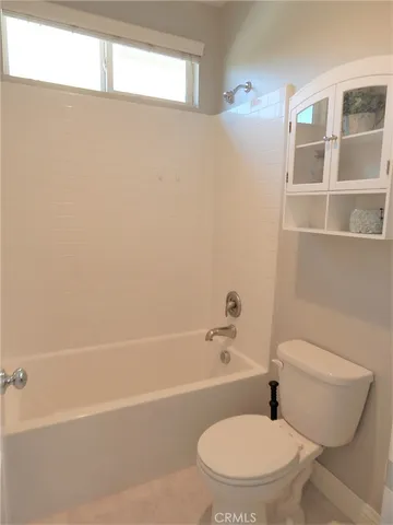a white toilet and tub sitting next to a window