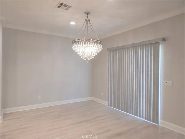 an empty room with chandelier fan and windows