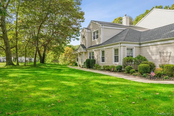 a view of a house with a big yard potted plants and large tree