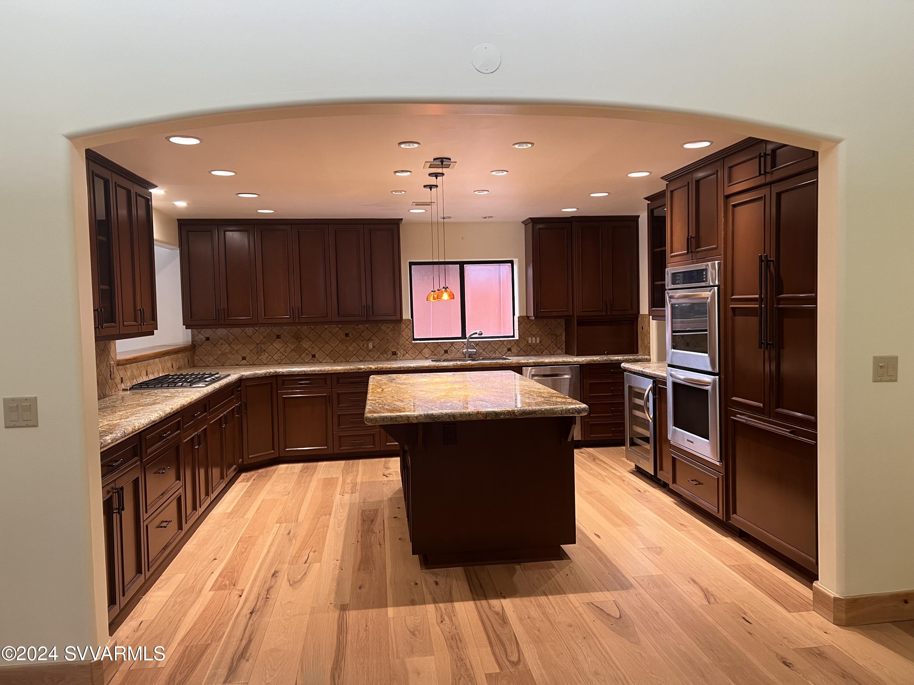 985 Rodeo Road Sedona, AZ 86336 - Photo 5 of 12 a kitchen with wooden floors and wooden cabinets