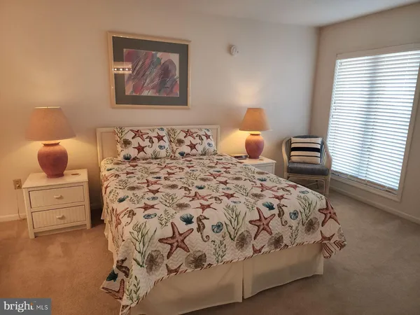 a bedroom with a bed and a lamp on dresser