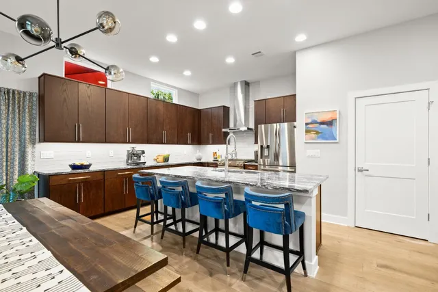 a kitchen with stainless steel appliances kitchen island granite countertop a table chairs and a refrigerator
