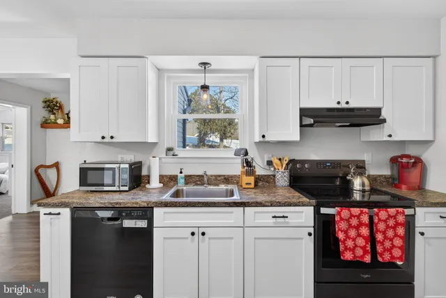 a kitchen with stainless steel appliances granite countertop a stove a sink a refrigerator and white cabinets