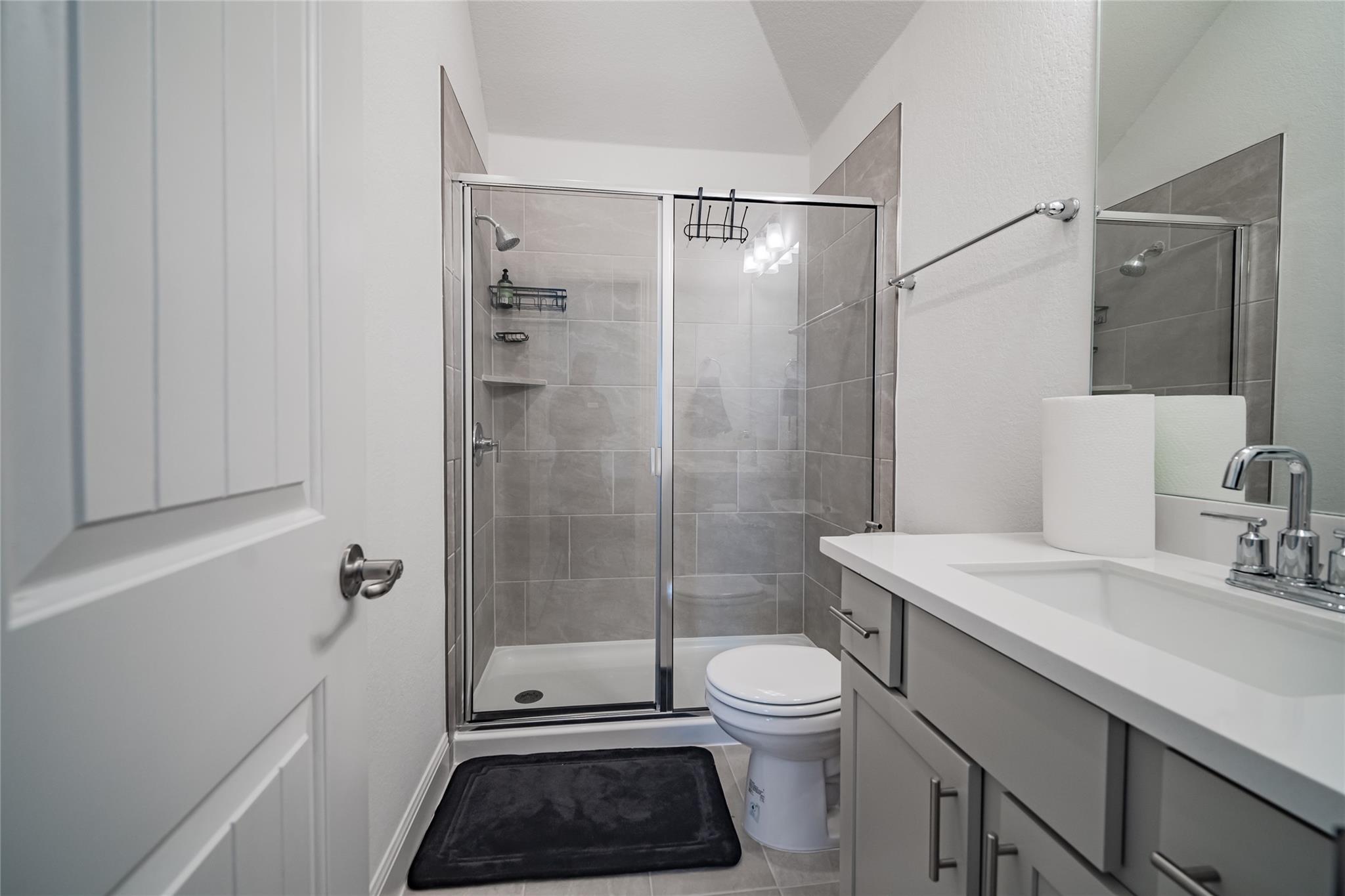 3049 Sage Ranch Drive Leander, TX 78641 - Photo 9 of 23 A well-appointed bath features a tiled walk-in shower and a modern vanity with ample counter space.